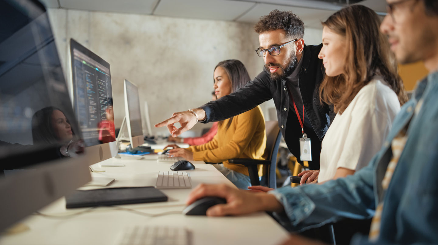 Salle de formation professionnelle moderne et lumineuse en grand angle avec des rangées d'ordinateurs portables ouverts sur des tables et de grandes fenêtres laissant entrer la lumière naturelle